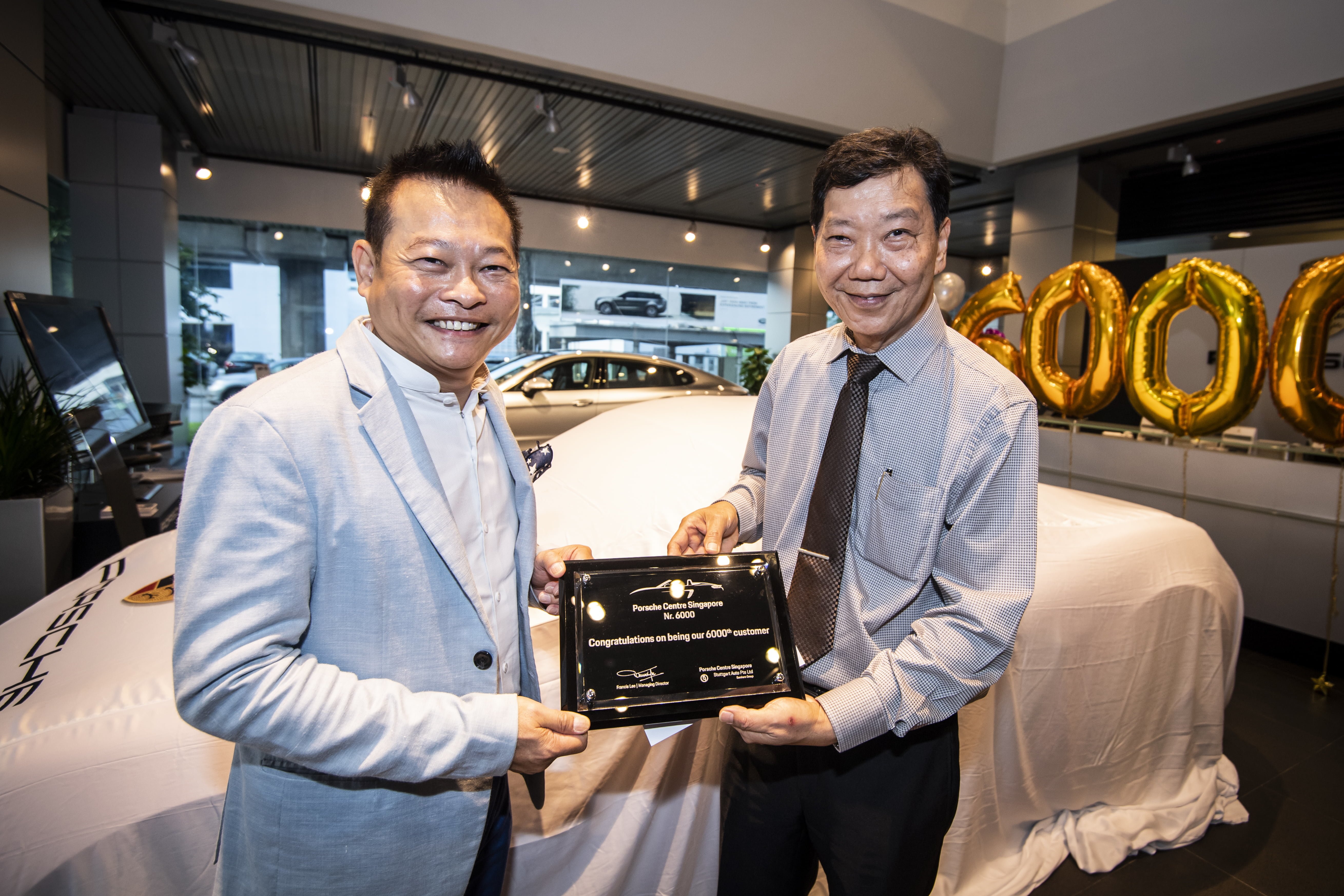 Mr Francis Lee, Managing Director of Stuttgart Auto (right) presenting a commemorative plaque to the new owner of the 6,000th Porsche car in Singapore, Mr Joe Goh